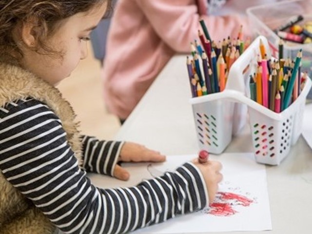 Child at desk drawing with coloured pencils